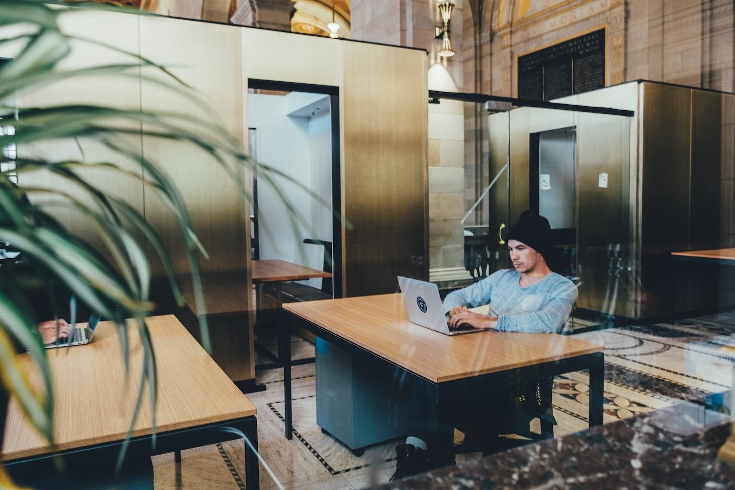 man working on laptop in shared office space - employee engagement